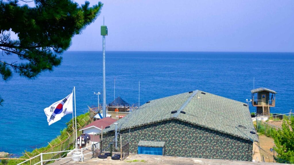 Nestled below the Daejin Lighthouse, a police and military building serves as a strategic lookout over the calm, blue waters of the East Sea.