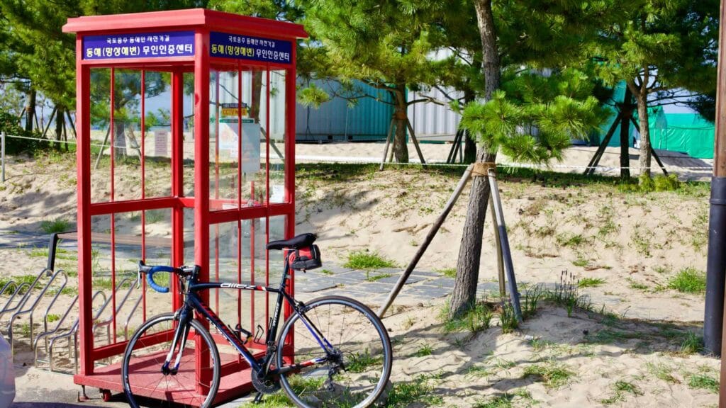 The Mangsang Beach Certification Center, where cyclists stamp their passports to track adventures along Korea's cross-country routes, set against sandy grounds and pine trees.