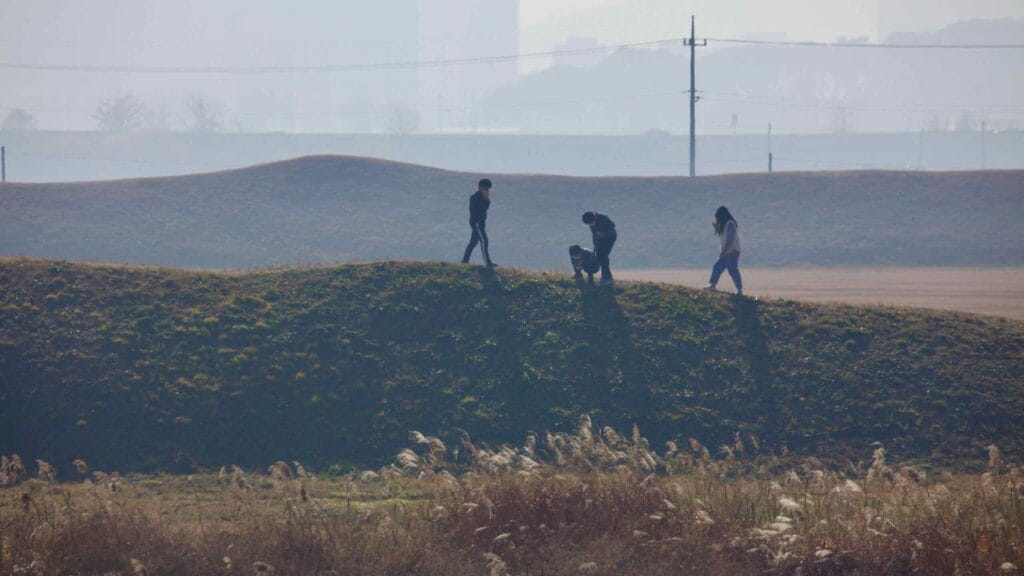 Visitors walks along the grassy embankments of Jeongbukdong Toseong Fortress.