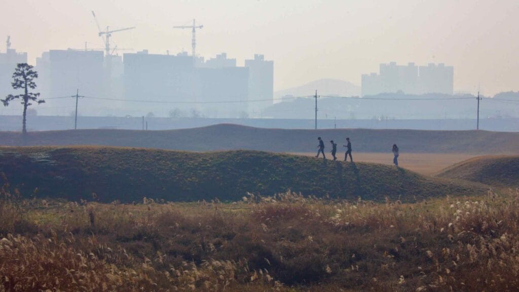 Visitors walk along the grassy earthen walls of Jeongbukdong Toseong Fortress.