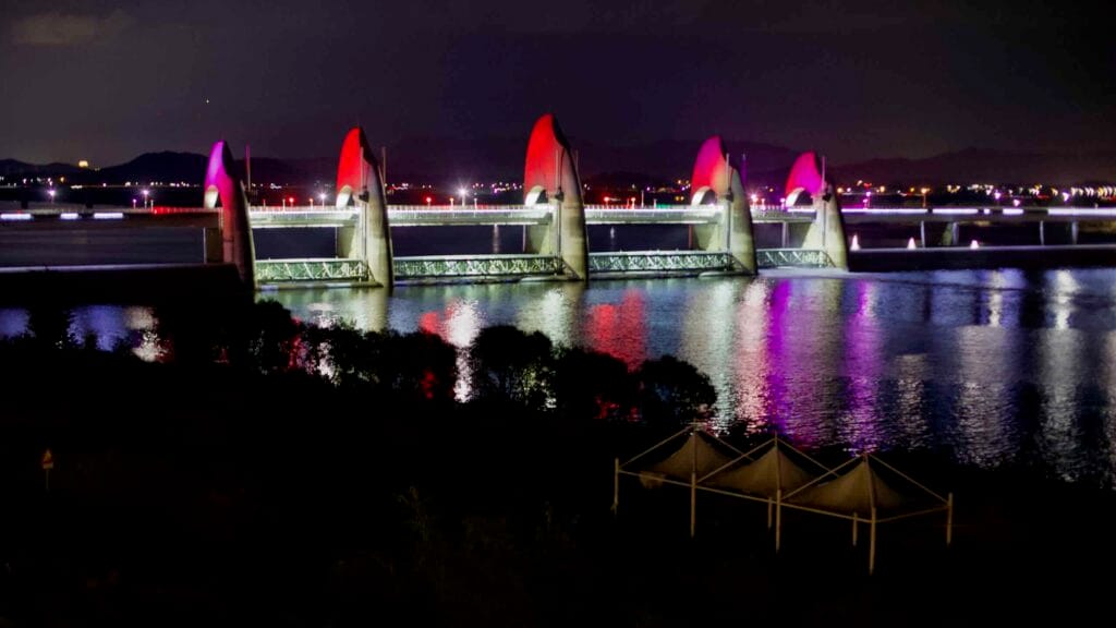 The Seungchon Weir on the Yeongsan River is illuminated in shades of red.
