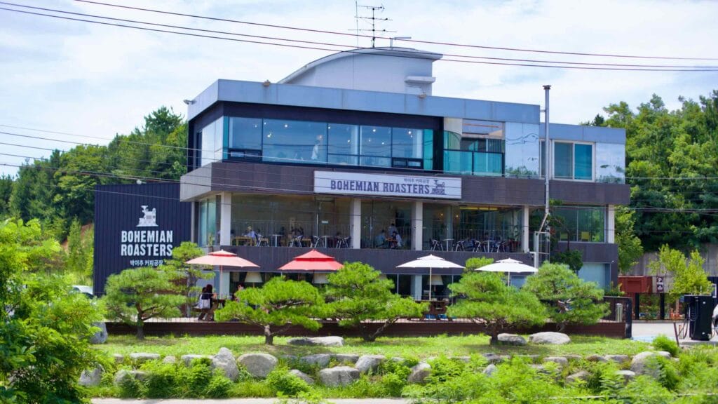 Nestled among green trees with a manicured lawn, the three-story Bohemian Roasters coffee shop offers an artisanal hand-drip coffee experience along the city's scenic coast.