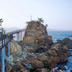 A view along the Chogok Yonggul Cave Hiking Trail, with a walking deck in the foreground, a tall rock observatory in the midground, and the East Sea in the background.