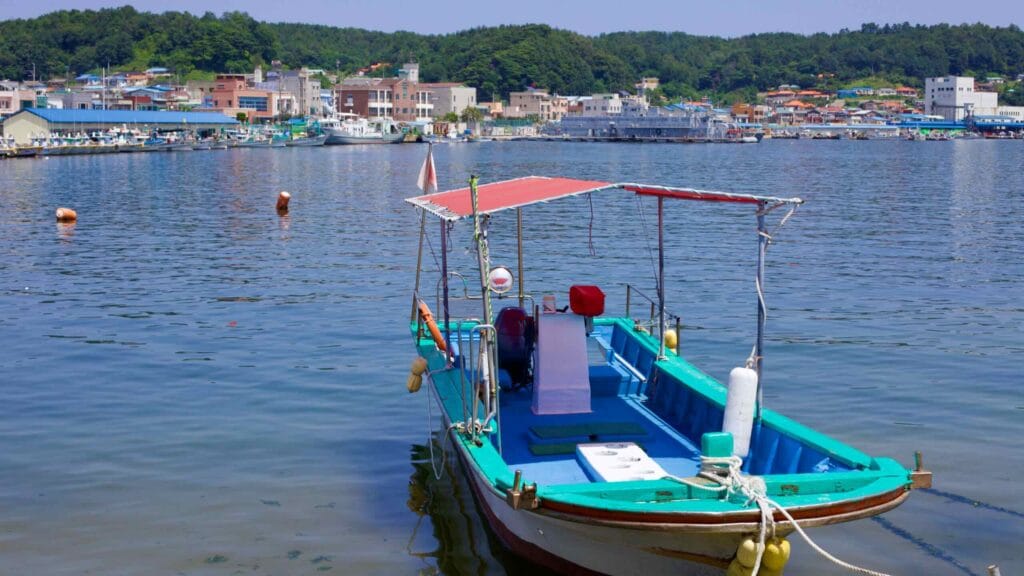 A boat is moored at the tranquil docks of Geojin, floating on calm, clear waters.
