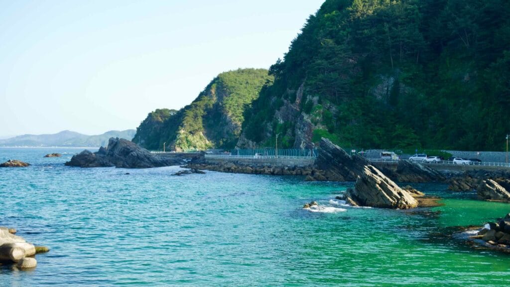 Heonhwa Road winds along the rocky coastline, with steep cliffs and turquoise waters of the East Sea.