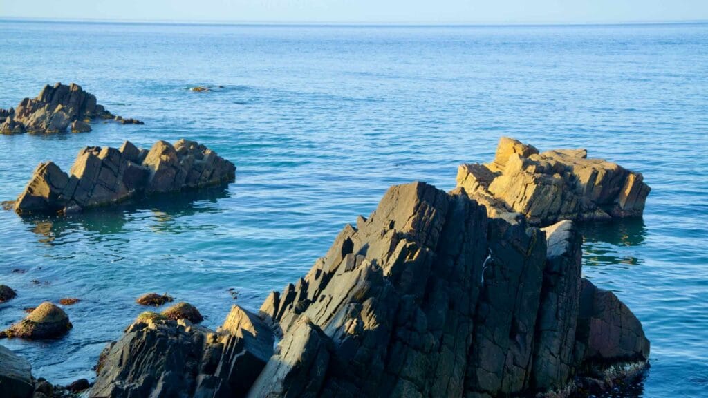 Rugged rock formations jutting out of the clear blue waters of the East Sea, near Jeongdongjin Beach.