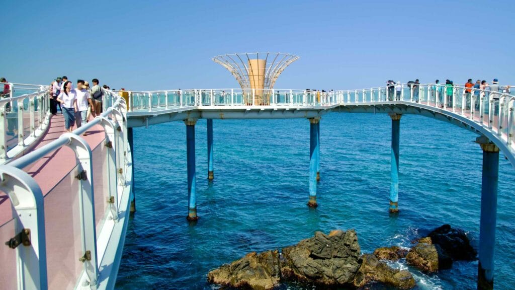 Tourists walk along the Dojebigol Haerang Observatory walkway, which extends over the East Sea.
