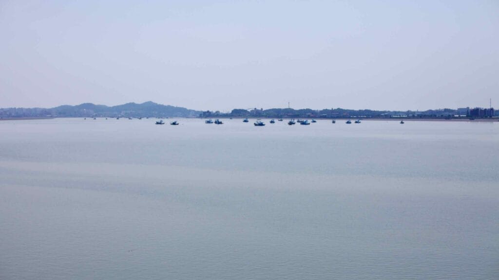 A fleet of fishing boats floats on the calm waters where the Geum River meets the Yellow Sea.