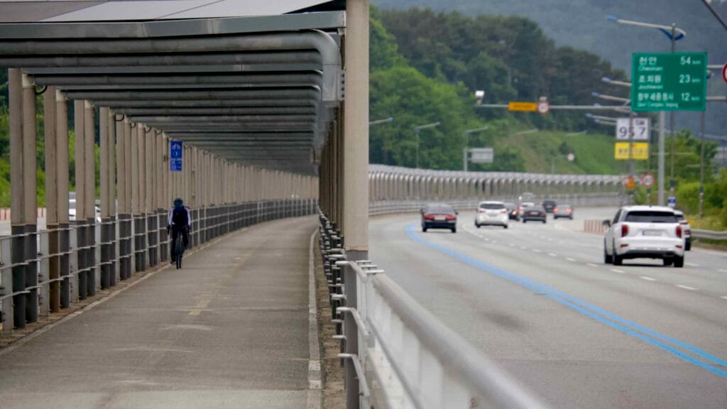 A cyclist rides along the covered bike path on North Star Road, shielded by solar panels.