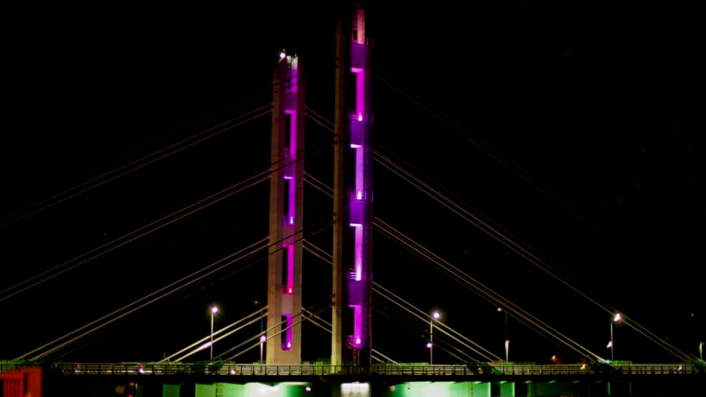 The Daecheong Bridge glows in vibrant purple and green lights against the dark night sky.
