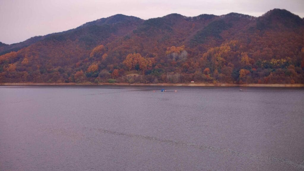 A view of Daecheong Lake with autumn foliage covering the surrounding mountains.