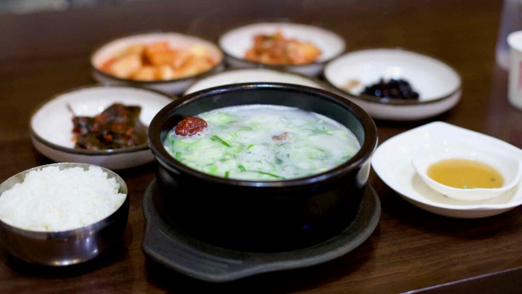 A traditional Korean meal featuring galbitang, a clear beef rib soup served with rice and banchan side dishes.
