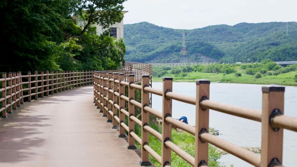 Wooden boardwalk by the Geum River, a peaceful path through lush greenery.