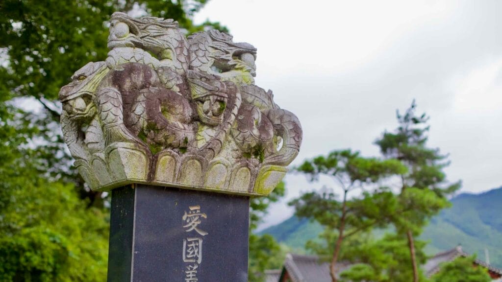 A historic stone monument in Yeonpung Town, adorned with intricate dragon carvings, stands as a tribute to patriotism and legacy, with traditional Korean architecture in the background.