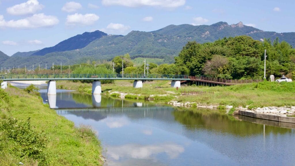 Bridge over the Yeongsan River; tranquil water reflects the sky, surrounded by mountains.