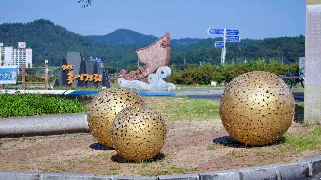 Hongeo Street entrance with golden spheres and sculpture, backed by mountains.