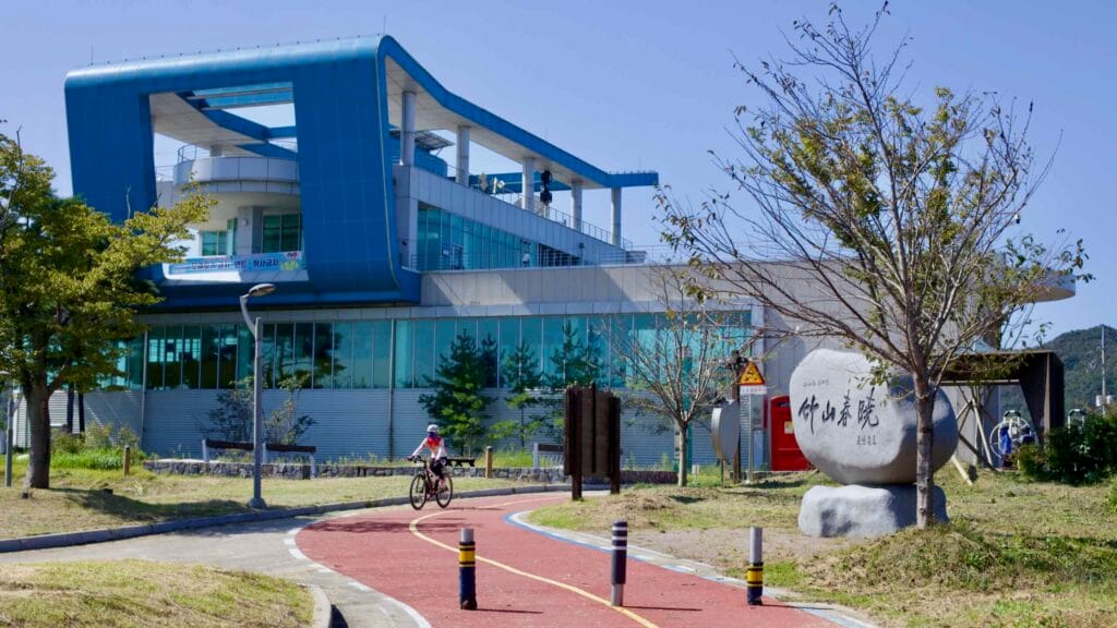 Cyclist passes Juksan Weir Management Center, an information and certification facility.
