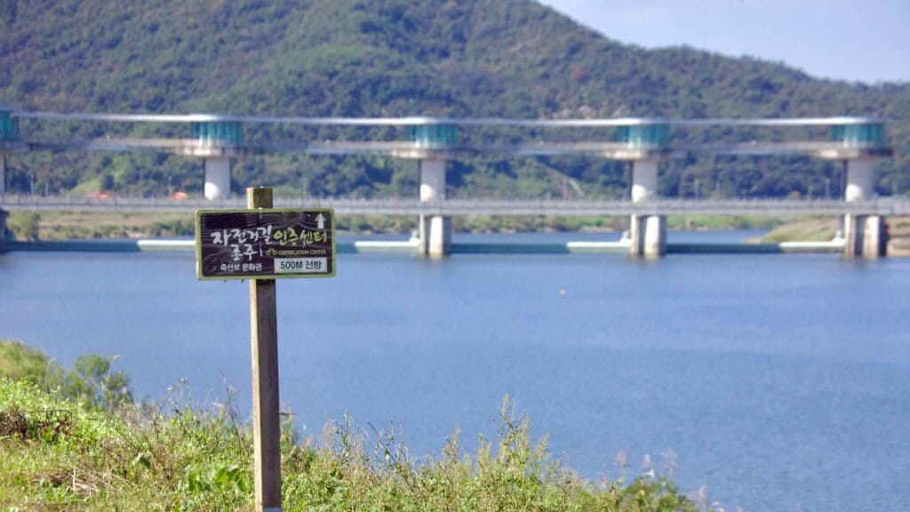 Wooden sign marks Juksanbo Certification Center (500m ahead); Juksan Weir in background.