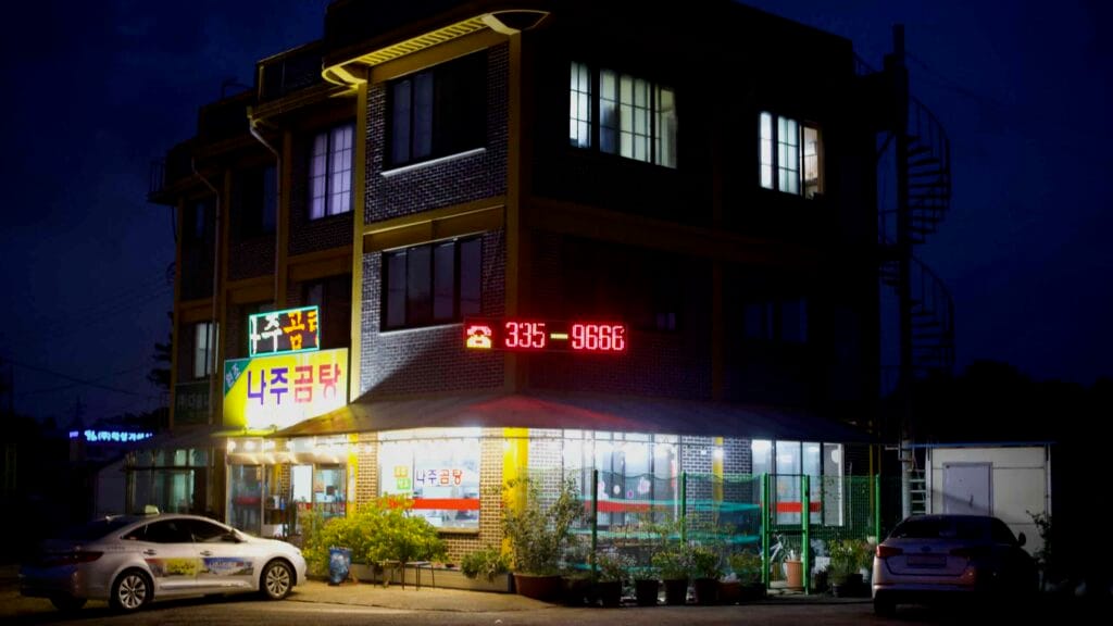 A Naju Gomtang restaurant glows under neon signage at night.