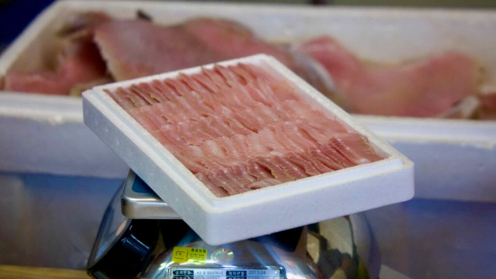 A neatly arranged tray of hongeo-hoe, fermented skate, is weighed on a scale at a seafood shop on Hongeo Street before being packaged for sale, highlighting the region’s traditional food trade.