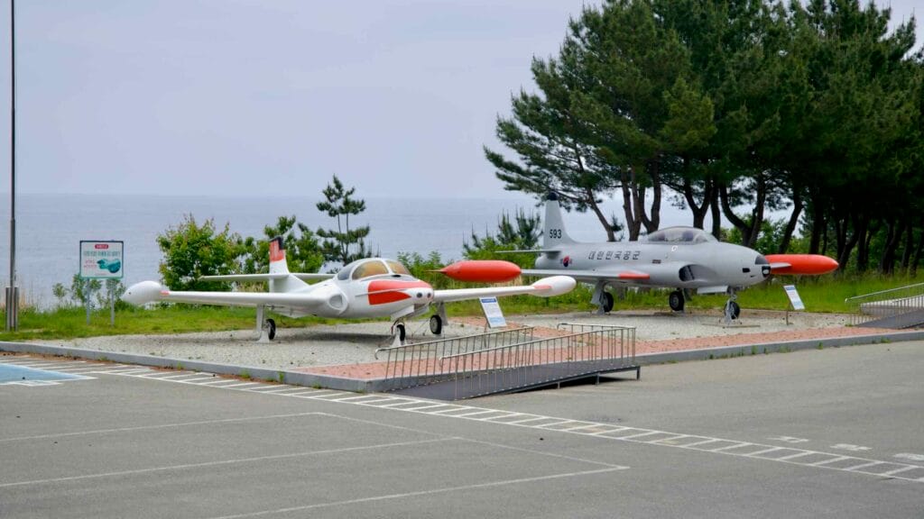 Retired training jets with orange tips near the East Sea shoreline at Gangneung Unification Park.