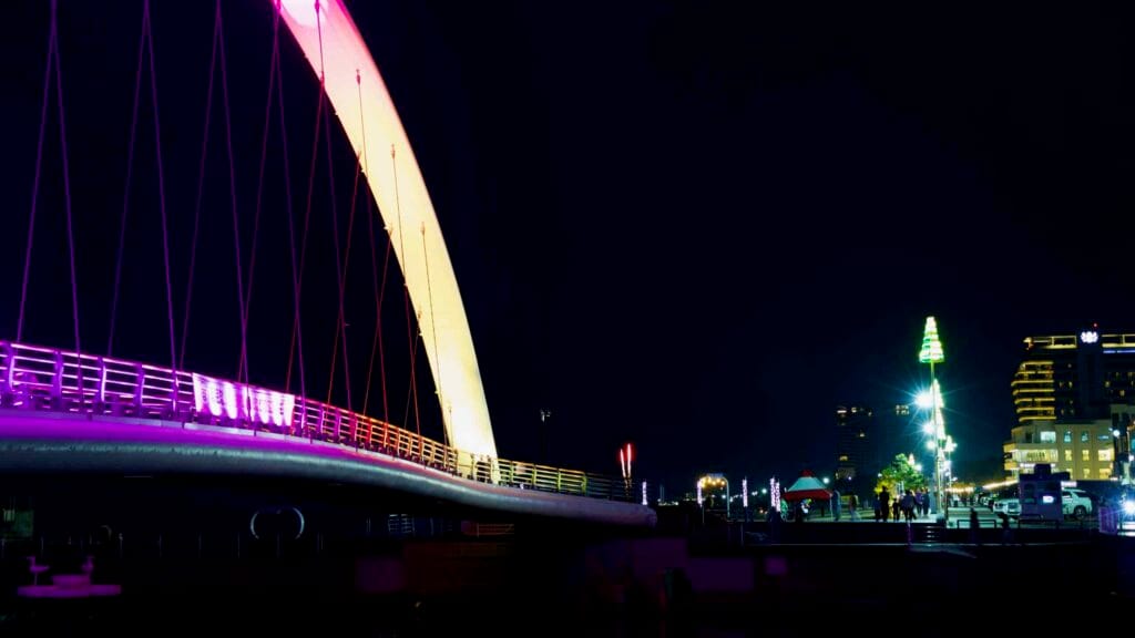 Gangmun Sotdae Bridge glowing in purple and gold, enhancing the coastal promenade at night.