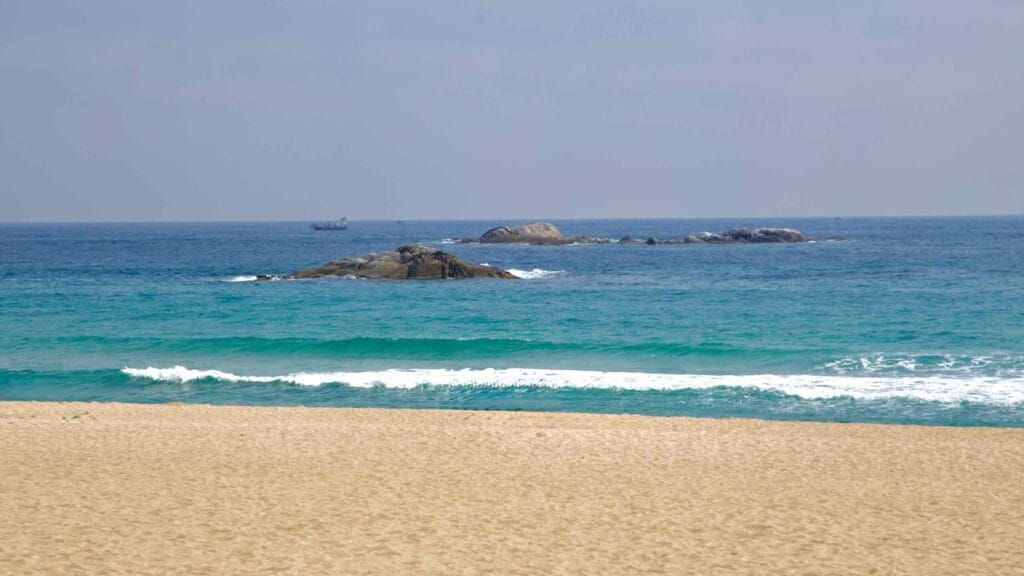 Gentle waves roll toward the shore of Gyeongpodae Beach, with rocky outcrops in the East Sea.