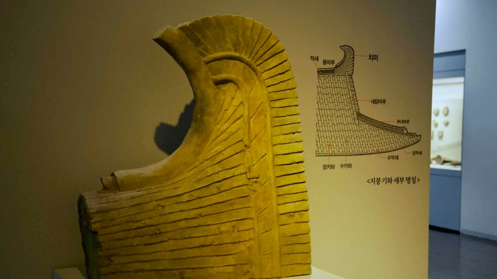 Traditional end tile from a historic Korean roof, displayed with a diagram in the Buyeo National Museum.