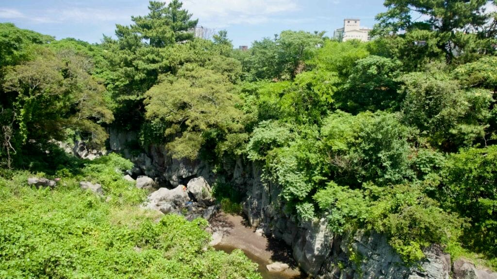 Basalt cliffs and shaded stream in Yongyeon Valley, Jeju City.