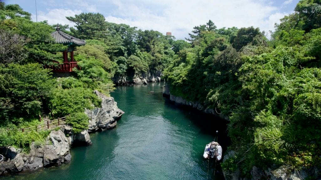 Basalt gorge and pavilion above green water at Yongyeon Valley.