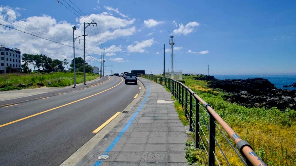 Curving coastal road and blue bike lane beside Eoyeong Park.