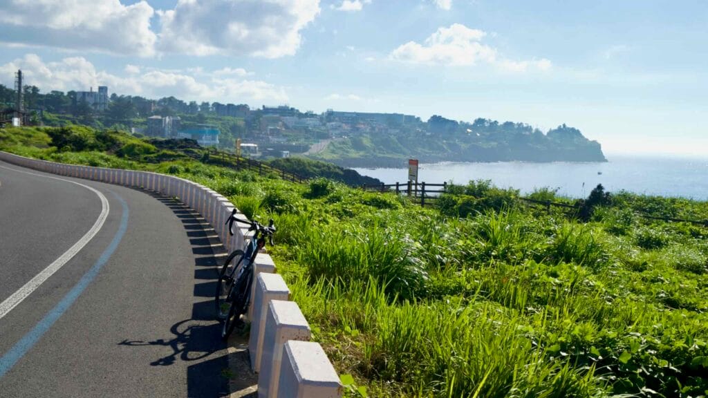 Road bike paused along the Hagu-Aewol Coastal Road above the bay.