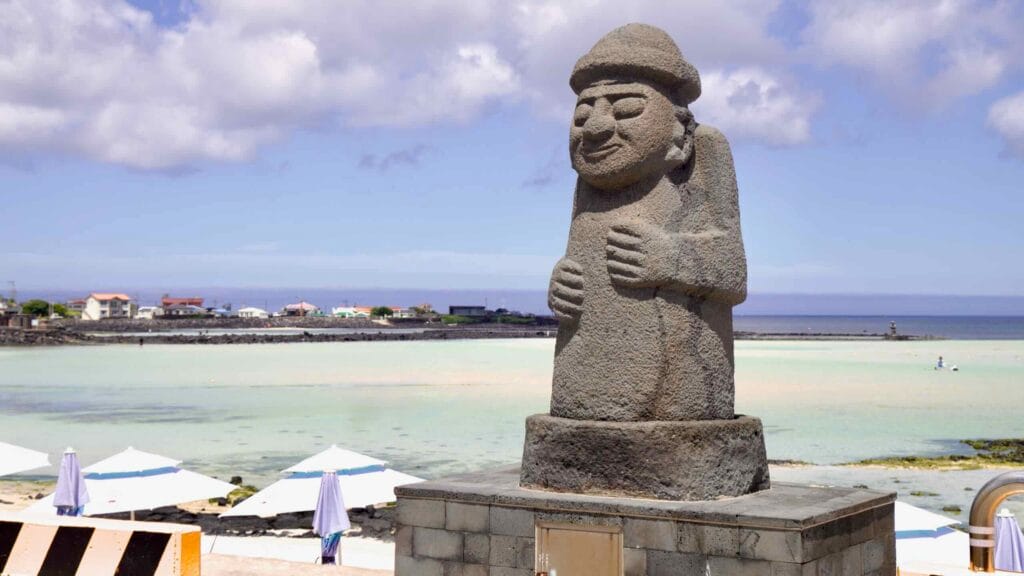 Dol hareubang by the seawall above Geumneung’s shallow lagoon.