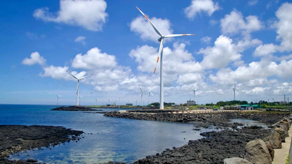 Wind farm over tide pools and volcanic rock under summer clouds.