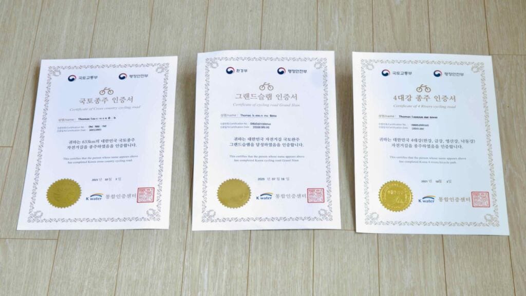 Official certificates for Korea’s top three cycling achievements: Cross-Country, Grand Slam, and 4 Rivers.