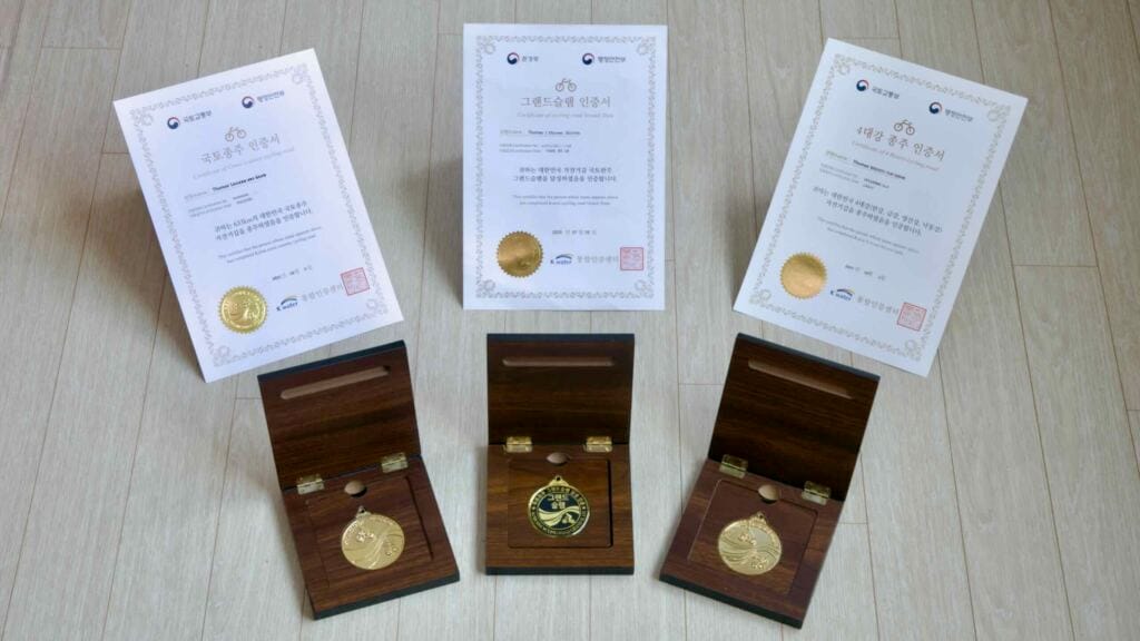 Certificates and medals for completing Korea’s Cross-Country, 4 Rivers, and Grand Slam cycling routes.