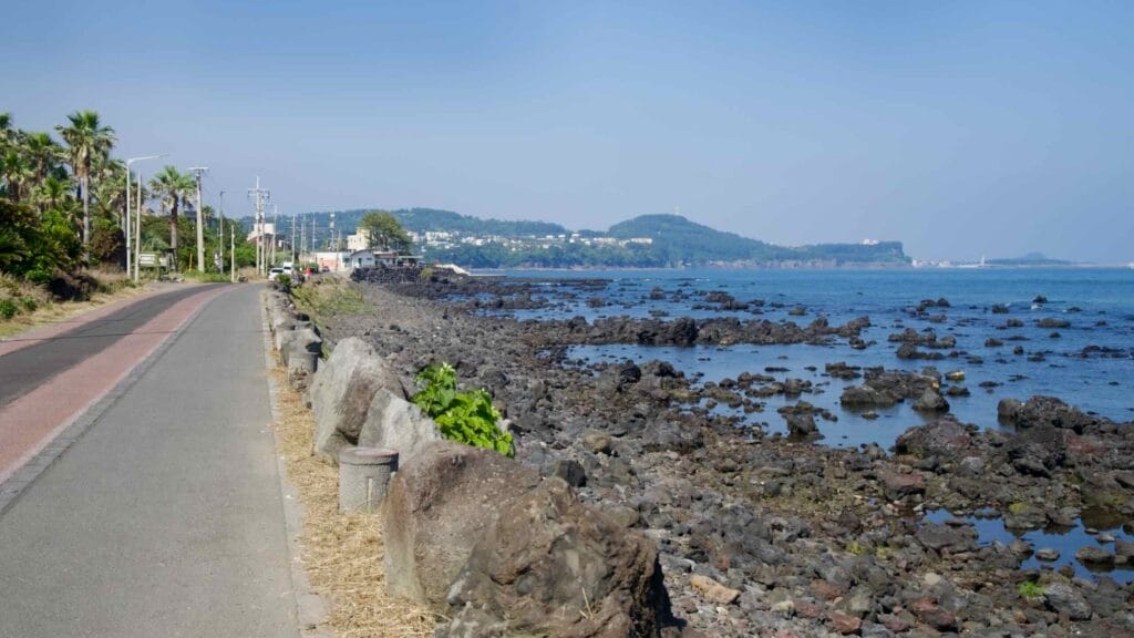 A long coastal path parallels the rocky foreshore toward headlands and villages.