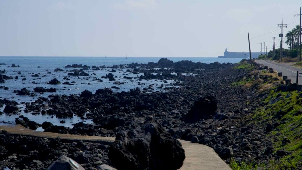 Rugged volcanic rocks line the coast toward the port.