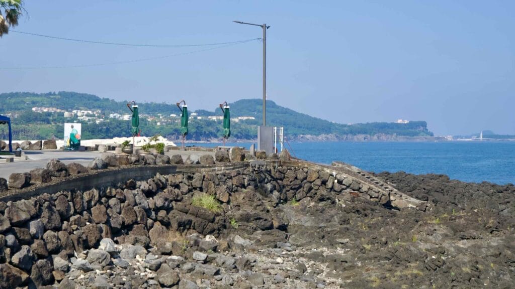 A rocky breakwater at Beophwan is lined with folded umbrellas.