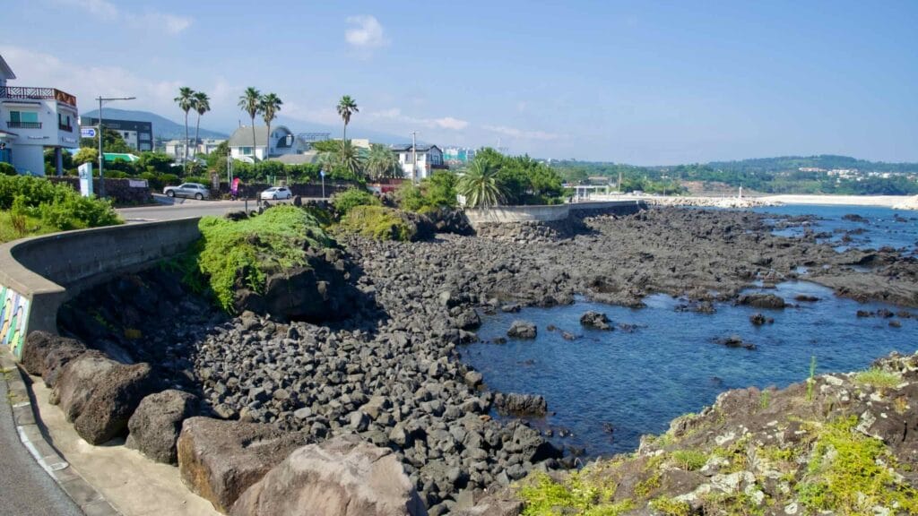 Palm trees and houses rise above the rocky coast of Beophwan.