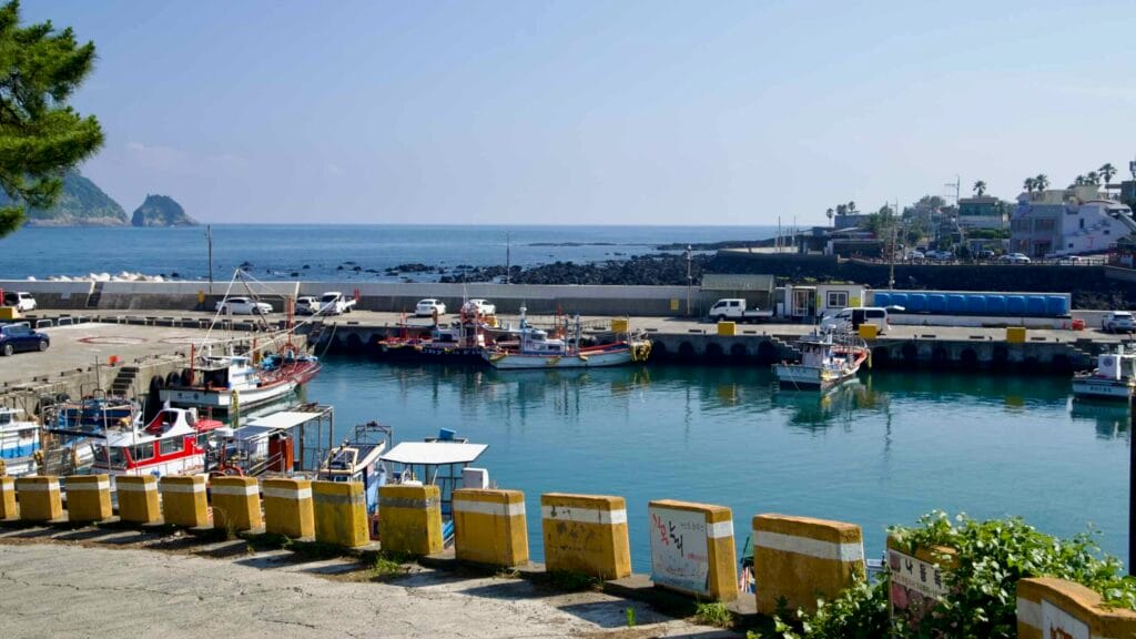 Fishing boats docked at Beophwan Harbor with islands in distance.