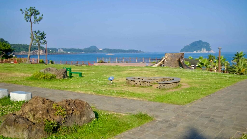 An open lawn and public art at Jaguri Culture & Arts Park frame a view of Seopseom Island.