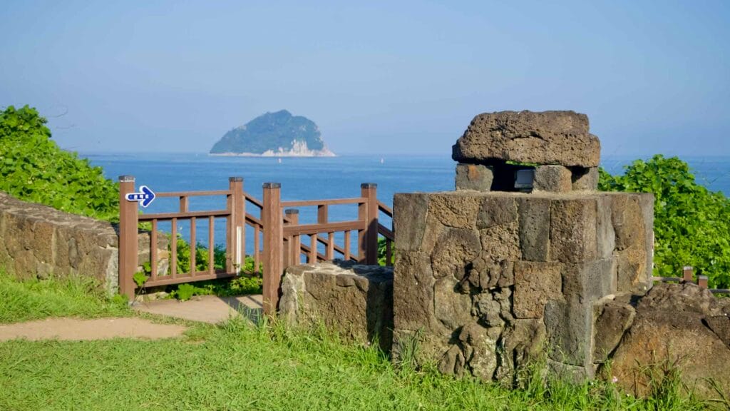 Basalt stonework frames a view of Seopseom Island from the Jaguri coastal path.