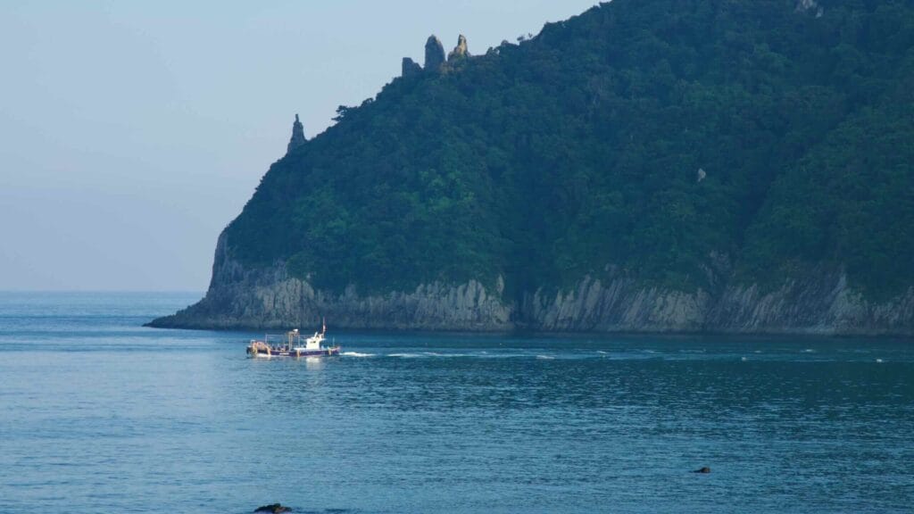 A workboat passes Seopseom Island's pinnacled headland.