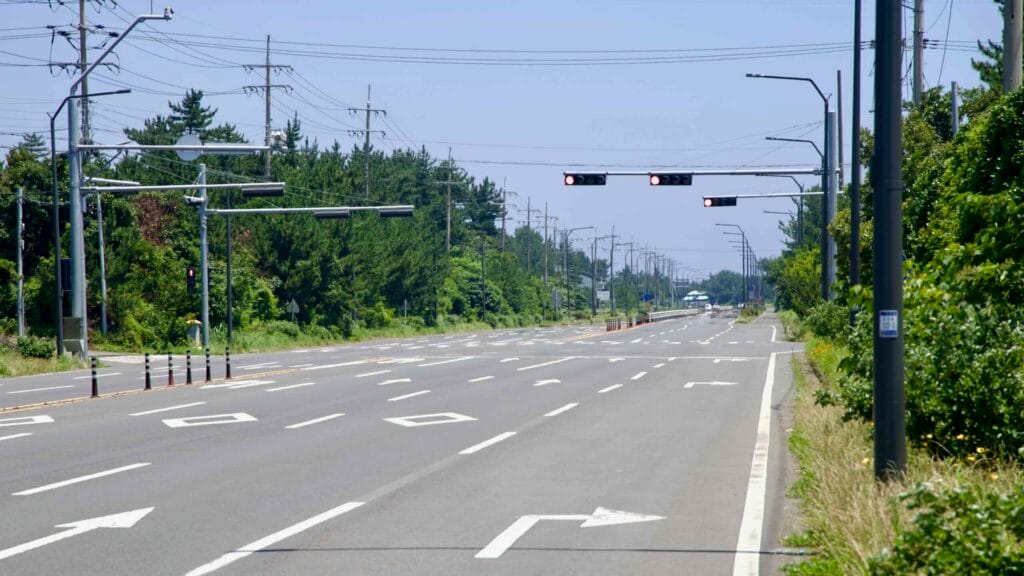 Iljudong Road runs quiet with signals, power lines, and coastal pines on Jeju’s east coast.