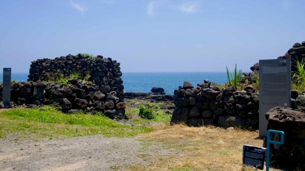 A gateway in the Sinsan Hwanhaejangseong opens to the basalt coast and sea.