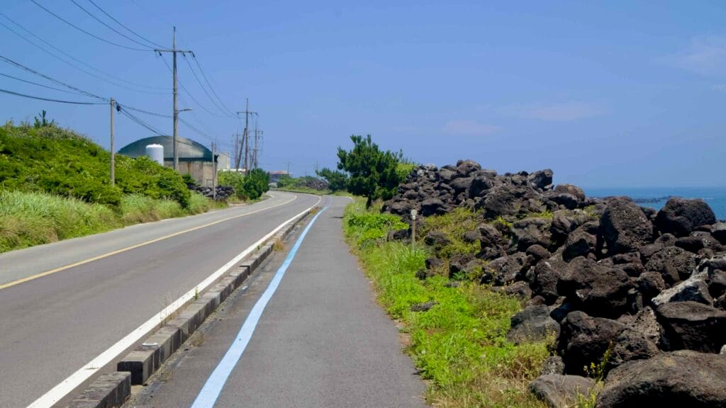 The coastal bike lane runs beside lava rocks and a quiet rural road.