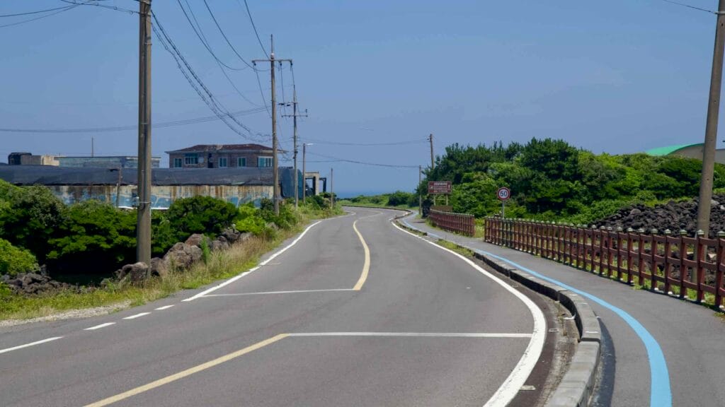 A curving coastal road and bikeway approach Onpyeong on Jeju’s east coast.