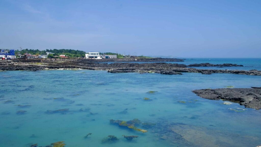 Turquoise shallows wash against layered lava ledges.