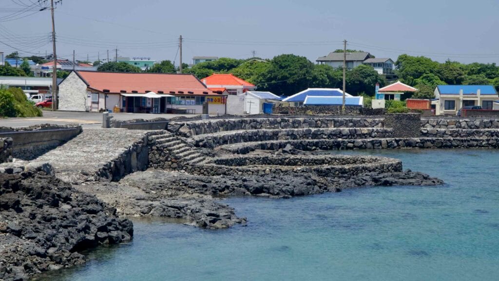 Stone steps meet shorefront shops above a calm cove.